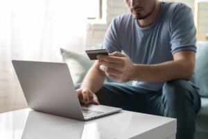 homem usando seu cartao de credito em frente ao computador