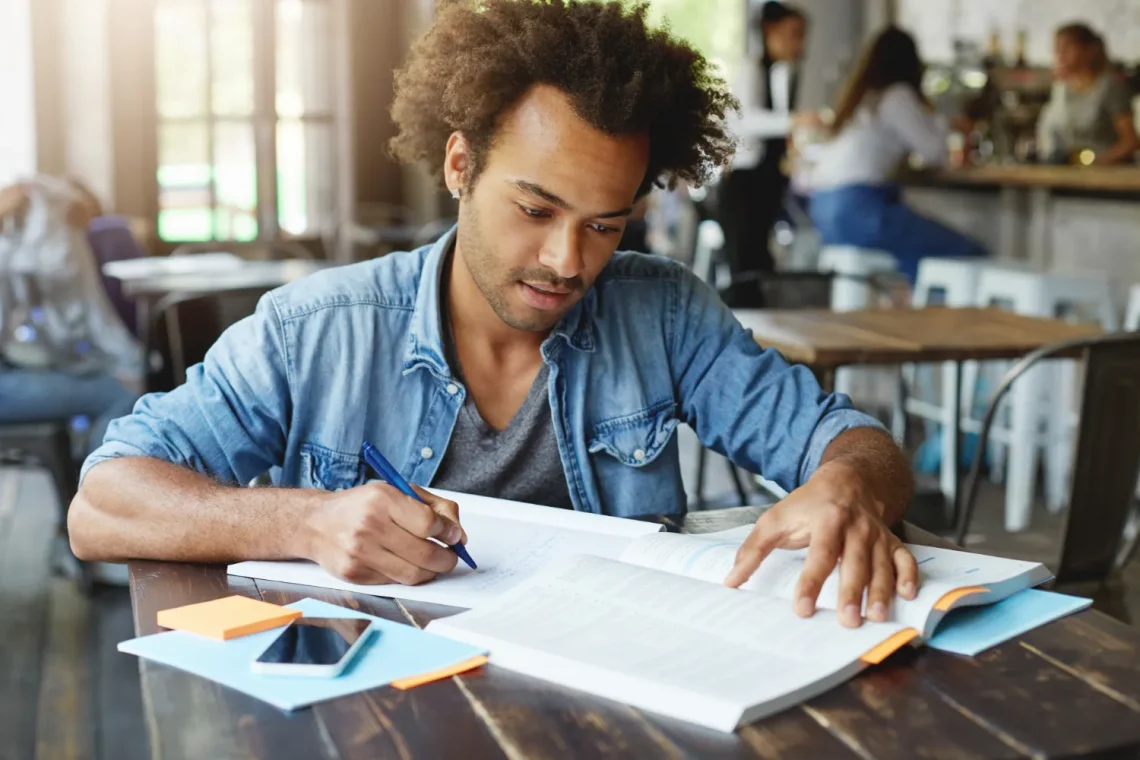 Homem estudando atentamente para concurso, com livros e anotações