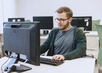 Técnico de Informática trabalhando em um ambiente de escritório com múltiplos computadores