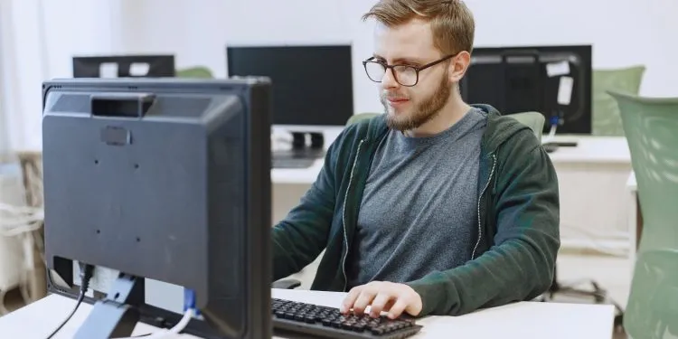 Técnico de Informática trabalhando em um ambiente de escritório com múltiplos computadores