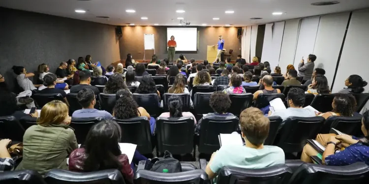 Sala de conferência com participantes ouvindo uma apresentação de palestra.