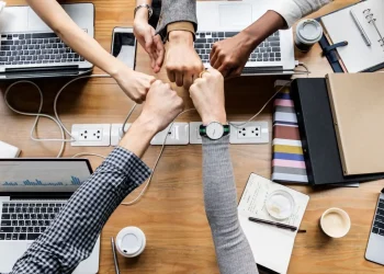 Equipe unida dando soquinho em um ambiente de trabalho colaborativo.
