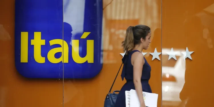 Mulher passando em frente ao banco Itaú, com o logo visível.