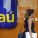 Mulher passando em frente ao banco Itaú, com o logo visível.