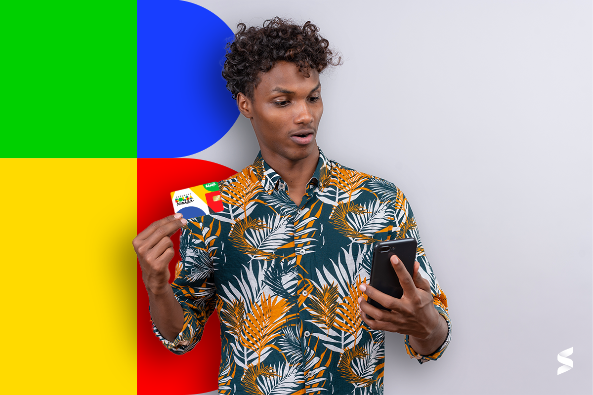 Homem segurando um cartão de crédito e um celular com um fundo colorido enquanto consulta informações, ilustrando o uso de aplicativos para acessar serviços como o NIS.