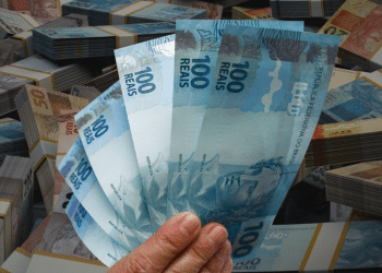 Notas de 100 reais em mãos, simbolizando as novas oportunidades de crédito.