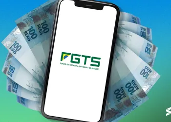 Celular exibindo o logotipo do FGTS com notas de 100 reais ao fundo, representando o saque do FGTS.
