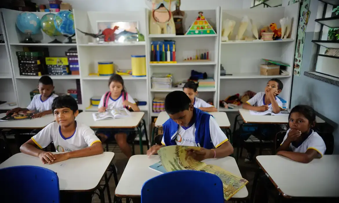 Crianças em sala de aula estudando e lendo livros.