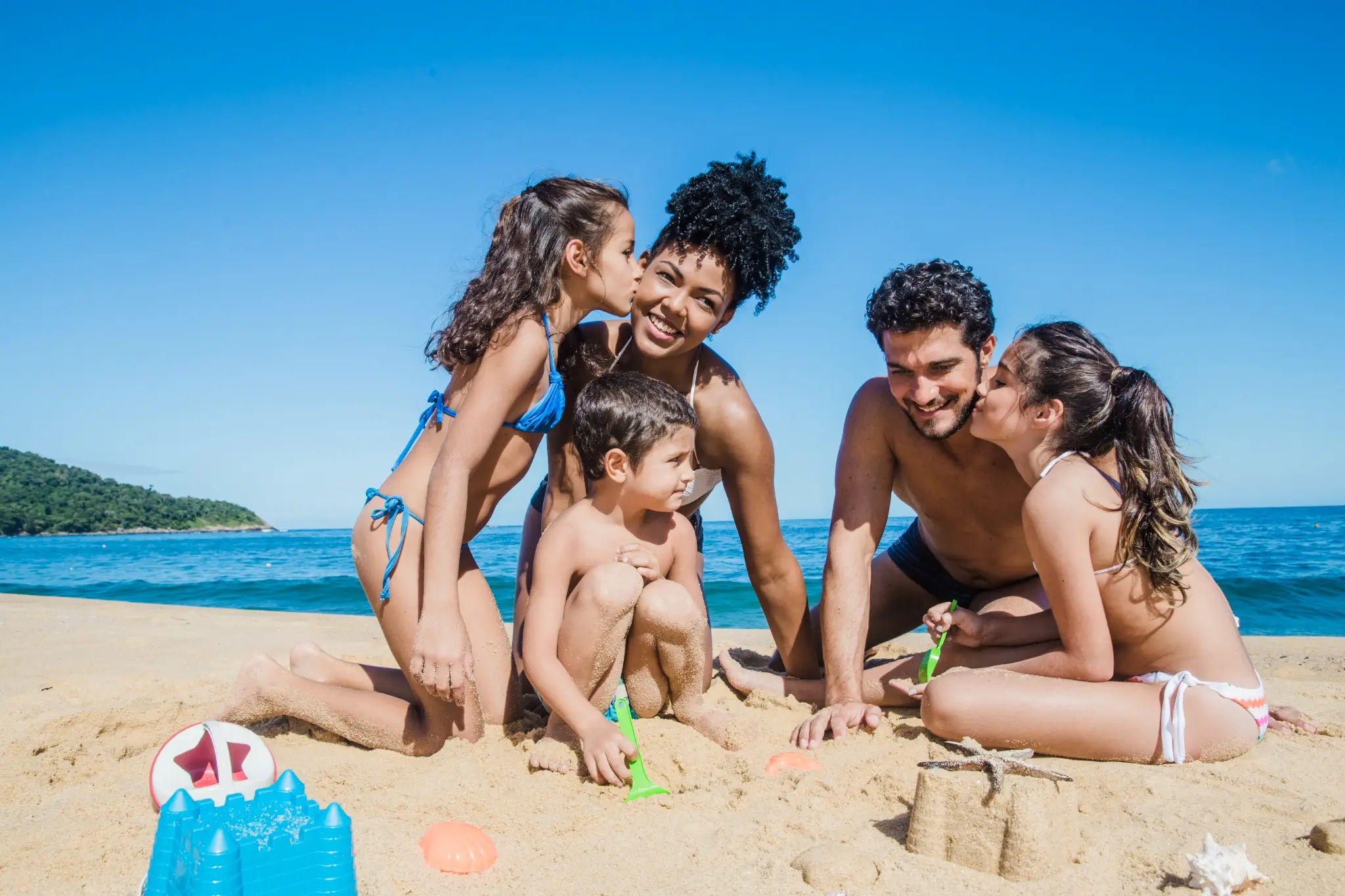 Família aproveitando um dia ensolarado na praia, brincando na areia.