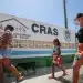 CRAS realizará visitas domiciliares para novos cadastros no Bolsa Família 8 Pessoas caminhando em frente a um centro do CRAS em dia ensolarado.
