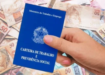 Carteira de Trabalho segurada por uma mão, com notas de dinheiro ao fundo, representando o consignado clt data.