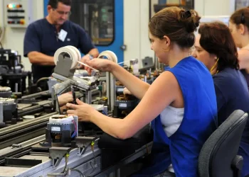 Trabalhadores em uma linha de produção, representando a importância do empreendedorismo e do mercado de trabalho.
