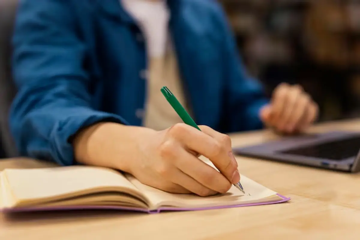 Pessoa escrevendo em caderno enquanto estuda para o Concurso Nacional Unificado (CNU) 2025.