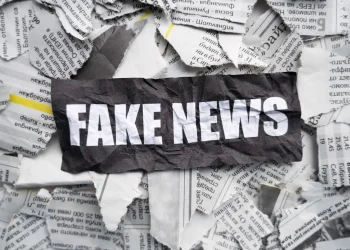 Imagem com recorte de jornal e a frase 'FAKE NEWS' sobreposta, representando desinformação em relação a comunicados falsos como o concurso correios fake news.
