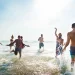 Grupo de amigos se divertindo no mar durante um dia ensolarado.
