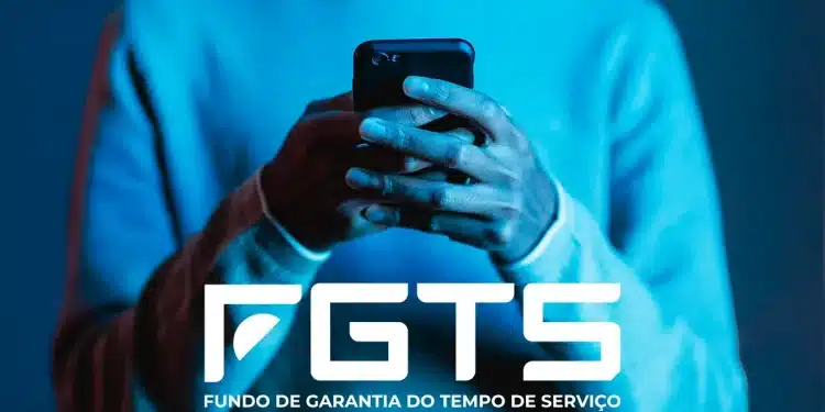 Data de pagamento do Saque-aniversário do FGTS de Março foi alterada 1 Mãos de uma pessoa segurando um smartphone com a logo do FGTS em destaque.