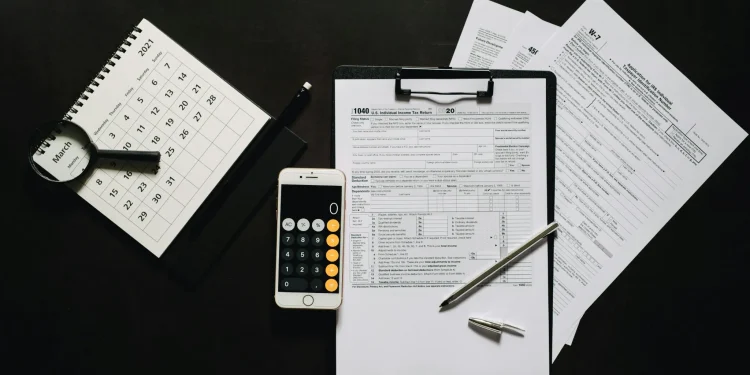 Documentos de imposto de renda, calculadora e calendário, ilustrando a isenção do IR até R$ 5 mil para 10 milhões de brasileiros.