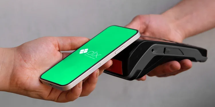 Pagamento via Pix sendo realizado com um smartphone em contato com uma maquininha de cartão.