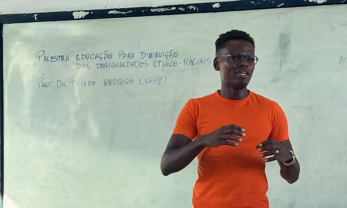Professor palestrante em sala de aula durante evento sobre educação, ilustrando o processo de inscrição para o Pé-de-Meia Licenciaturas.