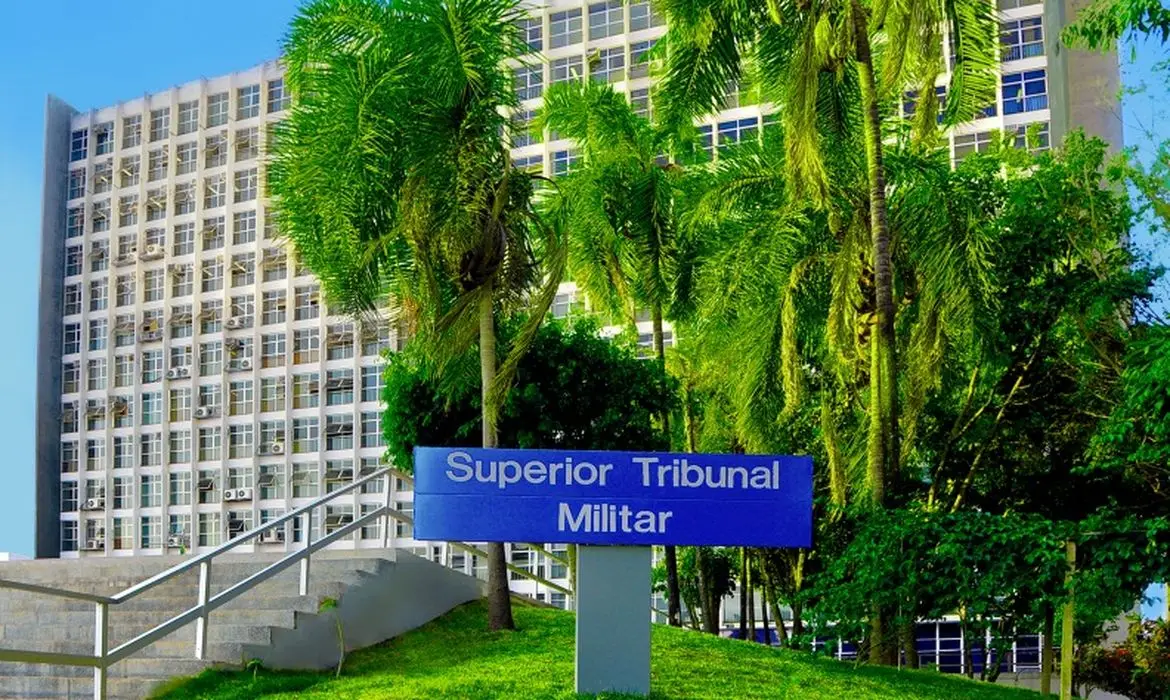 Fachada do Superior Tribunal Militar com placas e vegetação ao redor.