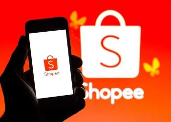 Logo da Shopee exibido em um celular, com fundo vermelho e a marca ao fundo, representando o trabalho na shopee