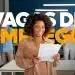 Mulher sorridente segurando papéis em um ambiente corporativo, com o texto 'Vagas de Emprego' em destaque.