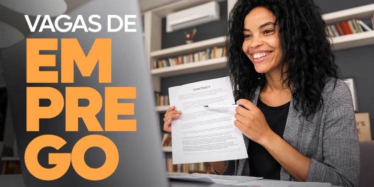 "Mulher sorrindo enquanto segura documentos em frente a um laptop, ilustrando uma vaga de emprego home office na C&A."