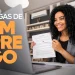 "Mulher sorrindo enquanto segura documentos em frente a um laptop, ilustrando uma vaga de emprego home office na C&A."