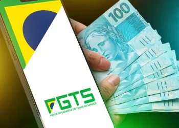 Celular exibindo o logo do FGTS ao lado de mãos segurando cédulas de 100 reais, representando o saque-aniversário do FGTS em 2025.