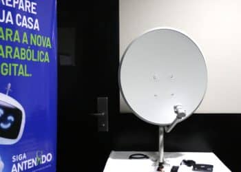 Antena parabólica digital branca em exposição com banner informativo.
