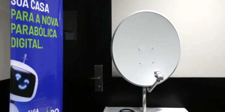 Antena parabólica digital branca em exposição com banner informativo.