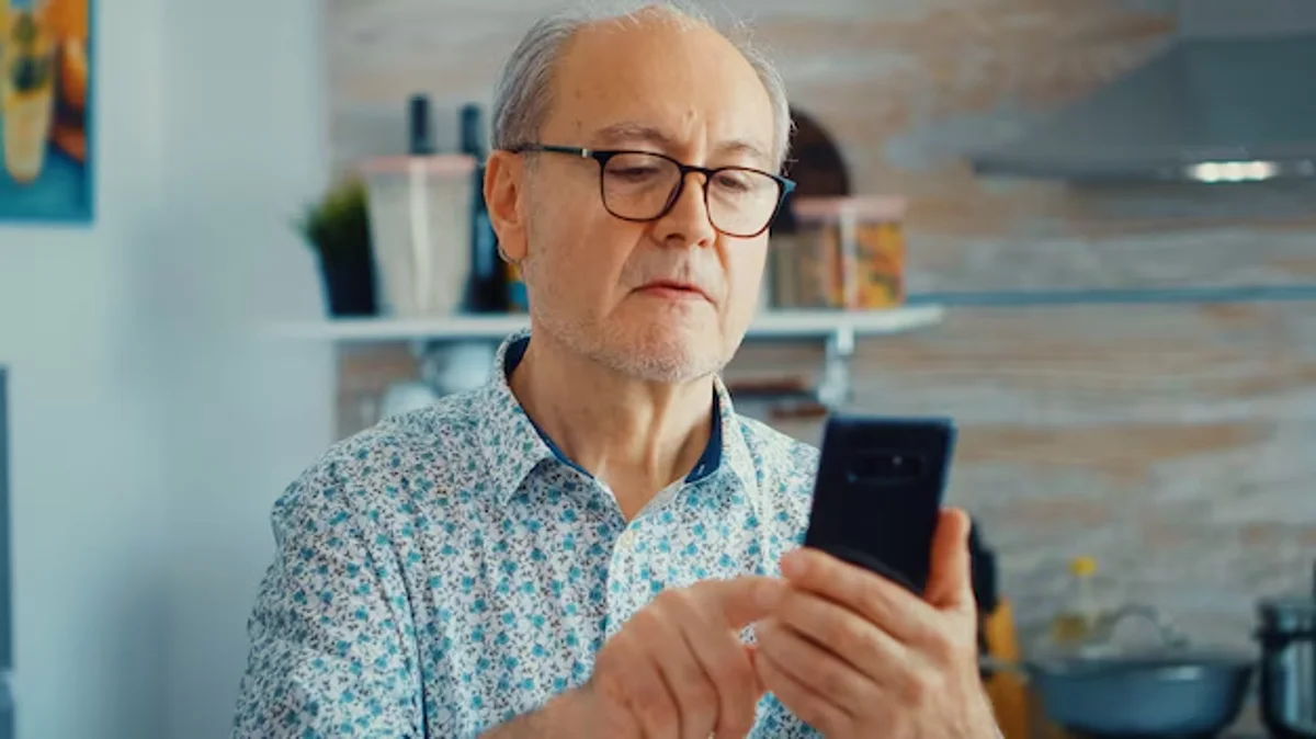 Homem idoso usando o celular para calcular ou verificar a aposentadoria.
