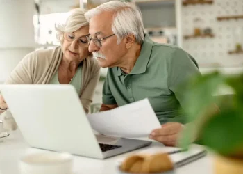Casal de idosos planejando aposentadoria e analisando documentos.