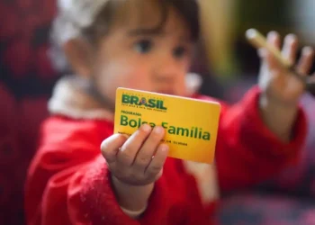 Criança segurando cartão do Bolsa Família, símbolo dos pagamentos sociais do programa em maio.