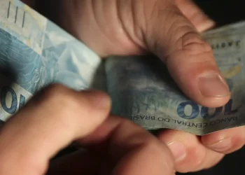 "Notas de 100 reais sendo contadas, representando os melhores salários de 2025 nas carreiras mais lucrativas."