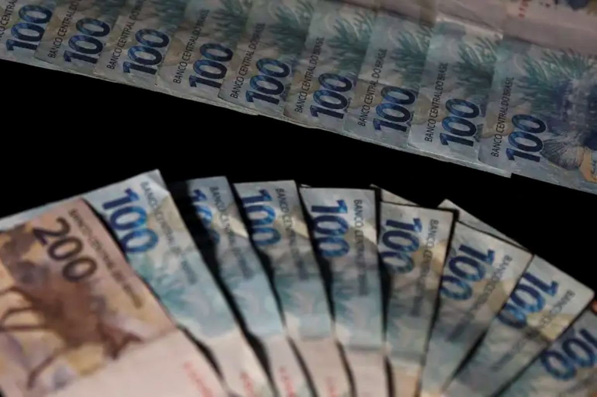 Cédulas de dinheiro brasileiro espalhadas, destacando notas de 100 e 200 reais.