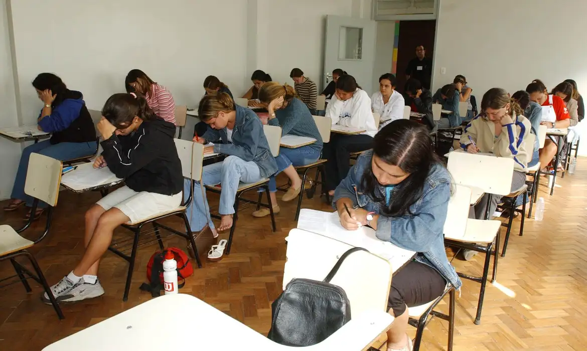 Estudantes concentrados fazendo prova em sala de aula.