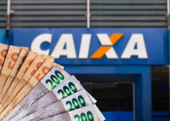 Dinheiro em espécie em frente a agência da Caixa Econômica Federal, ilustrando o pagamento do PIS 2025 para trabalhadores nascidos em maio e junho.