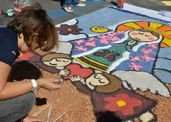 Arte em rua durante o feriado de Corpus Christi com figuras coloridas feitas com flores e pó colorido.