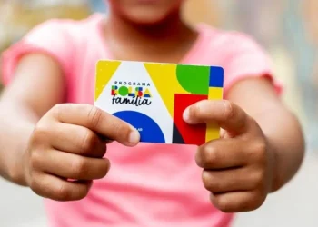 Cartão do Programa Bolsa Família sendo segurado por uma criança, com cores vibrantes e logo visível.
