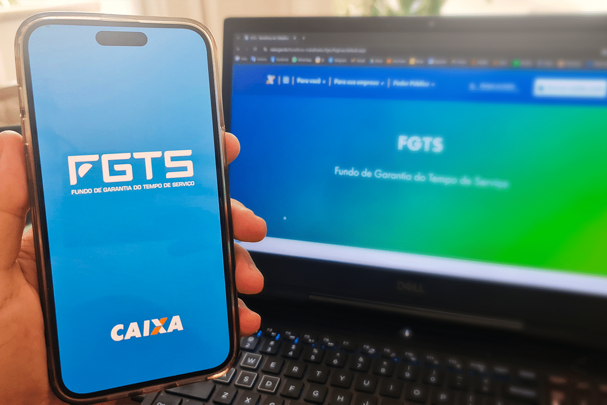 Tela de celular com logo do FGTS e site da Caixa no computador