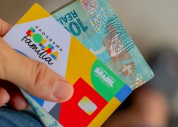 Cartão do Programa Bolsa Família com cédula de 100 reais