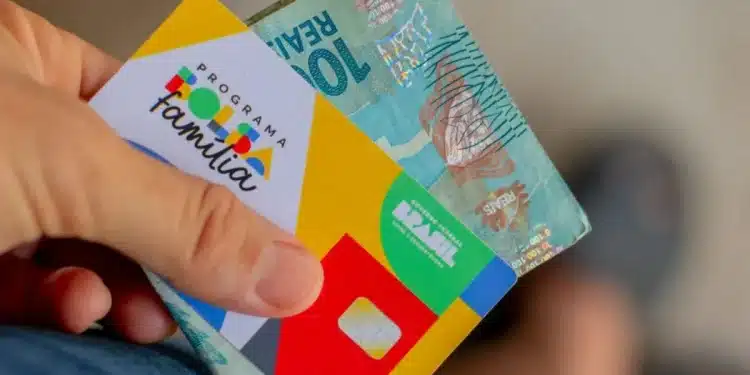 Cartão do Programa Bolsa Família com cédula de 100 reais