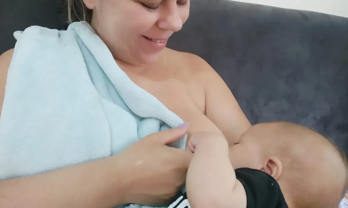 Momento de amamentação entre mãe e bebê após alta hospitalar, com foco no vínculo e cuidado.