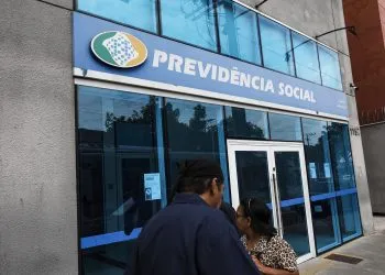 Agência do INSS mostrando o logo da Previdência Social e pessoas nas proximidades