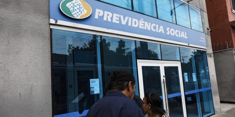 Agência do INSS mostrando o logo da Previdência Social e pessoas nas proximidades