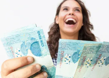 Mulher sorrindo com notas de 100 reais, representando apoio financeiro do programa Mães de Pernambuco 2025