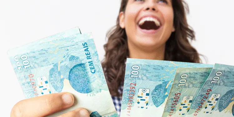 Mulher sorrindo com notas de 100 reais, representando apoio financeiro do programa Mães de Pernambuco 2025