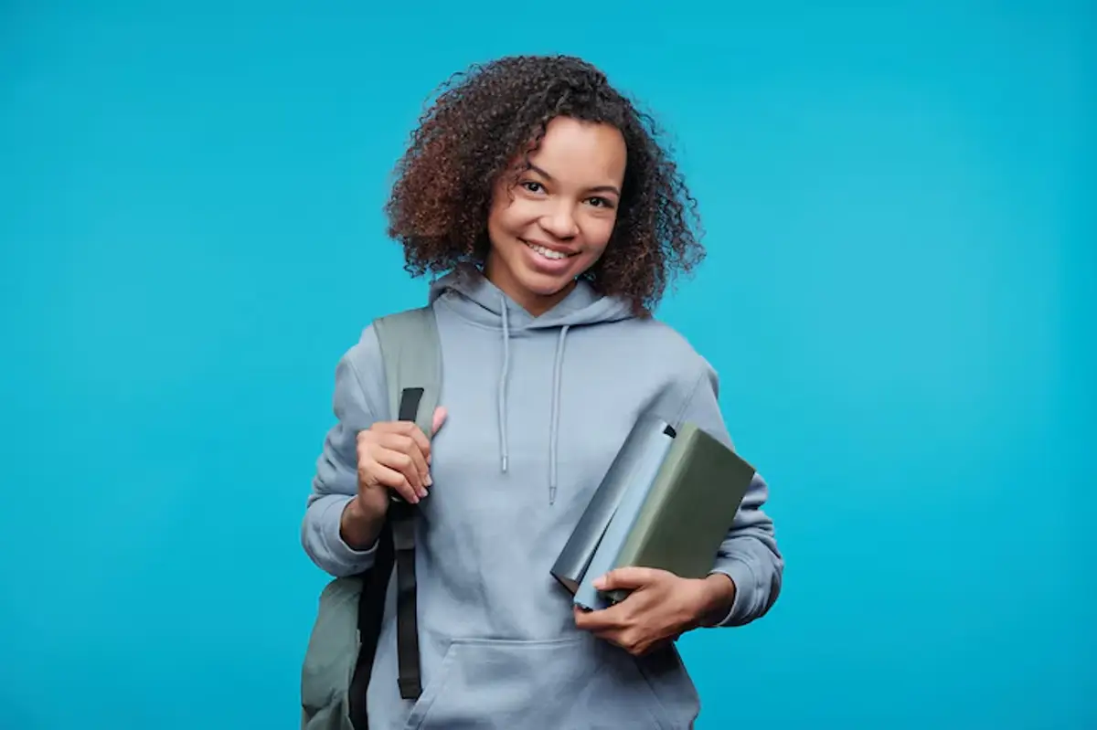 Estudante sorridente com mochila e livros, representando foco em estudos e preparação para a licenciatura.