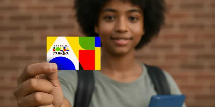 Jovem segura cartão do programa Bolsa Família em frente à câmera com expressão sorridente